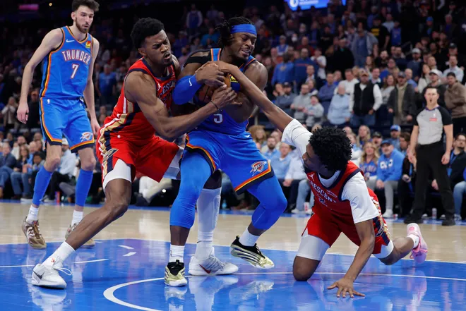Jan 27, 2026; Oklahoma City, Oklahoma, USA; Oklahoma City Thunder guard Luguentz Dort (5) fights for control of the ball against New Orleans Pelicans center Yves Missi (21) and forward Herbert Jones (2) during the second half at Paycom Center. Mandatory Credit: Alonzo Adams-Imagn Images