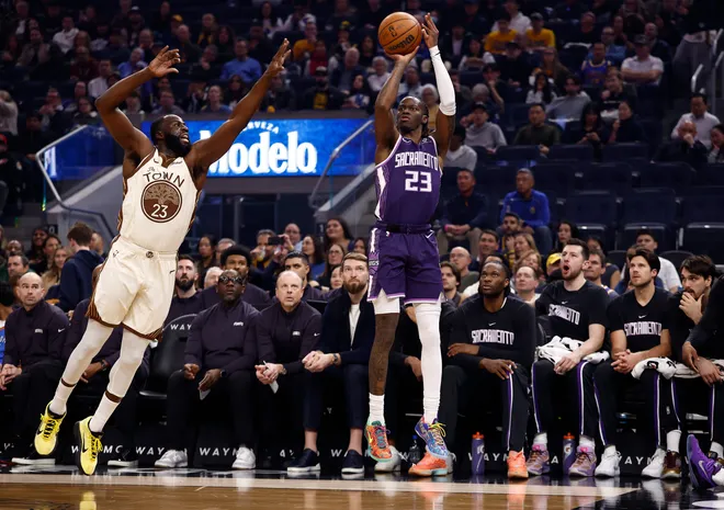 Jan 9, 2026; San Francisco, California, USA; Sacramento Kings guard Keon Ellis (23) scores a three point basket against Golden State Warriors forward Draymond Green (23) during the first quarter at Chase Center. Mandatory Credit: Kelley L Cox-Imagn Images