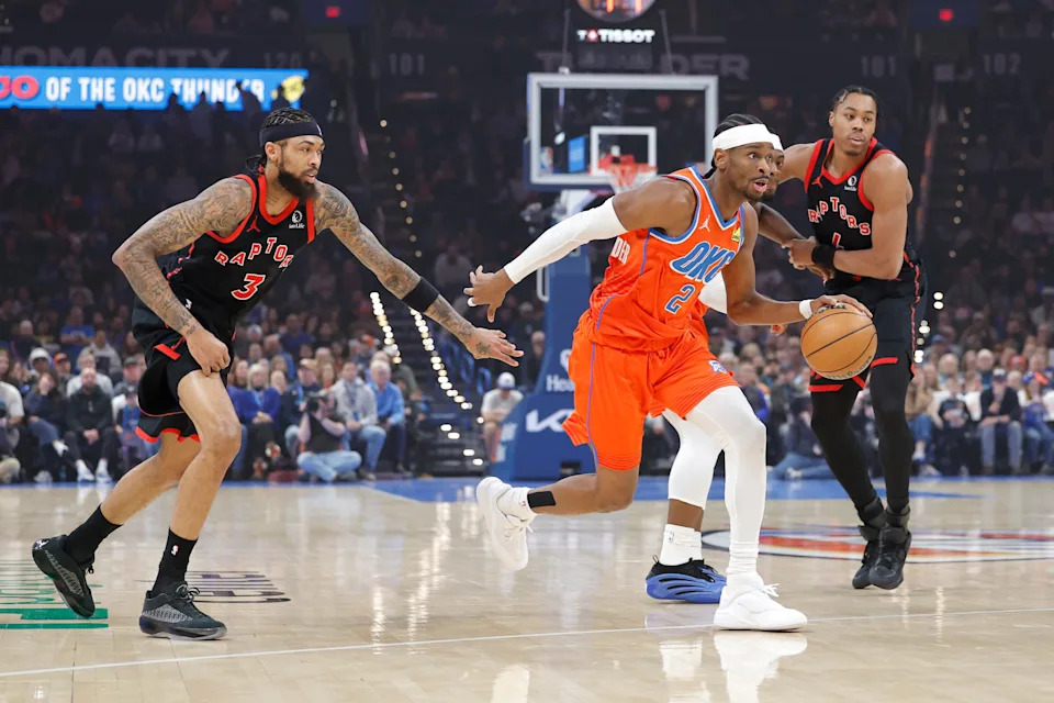 Jan 25, 2026; Oklahoma City, Oklahoma, USA; Oklahoma City Thunder guard Shai Gilgeous-Alexander (2) drives between Toronto Raptors forward Brandon Ingram (3) and Toronto Raptors guard Scottie Barnes (4) during the first quarter at Paycom Center. Mandatory Credit: Alonzo Adams-Imagn Images