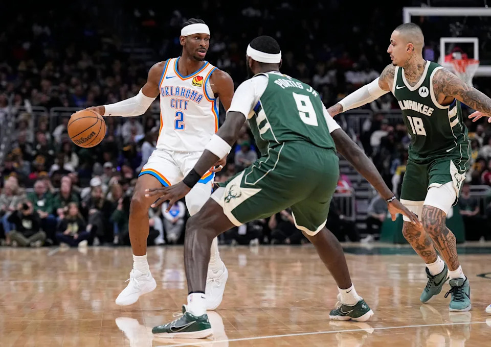 Jan 21, 2026; Milwaukee, Wisconsin, USA; Oklahoma City Thunder guard Shai Gilgeous-Alexander (2) drives to the basket against Milwaukee Bucks forward Bobby Portis (9) and Milwaukee Bucks forward Kyle Kuzma (18) in the first half at Fiserv Forum. Mandatory Credit: Michael McLoone-Imagn Images