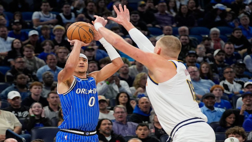 Orlando Magic guard Anthony Black (0) shoots over Denver Nuggets center Nikola Jokic during the first half of an NBA basketball game, Saturday, Dec. 27, 2025, in Orlando, Fla. (AP Photo/John Raoux)