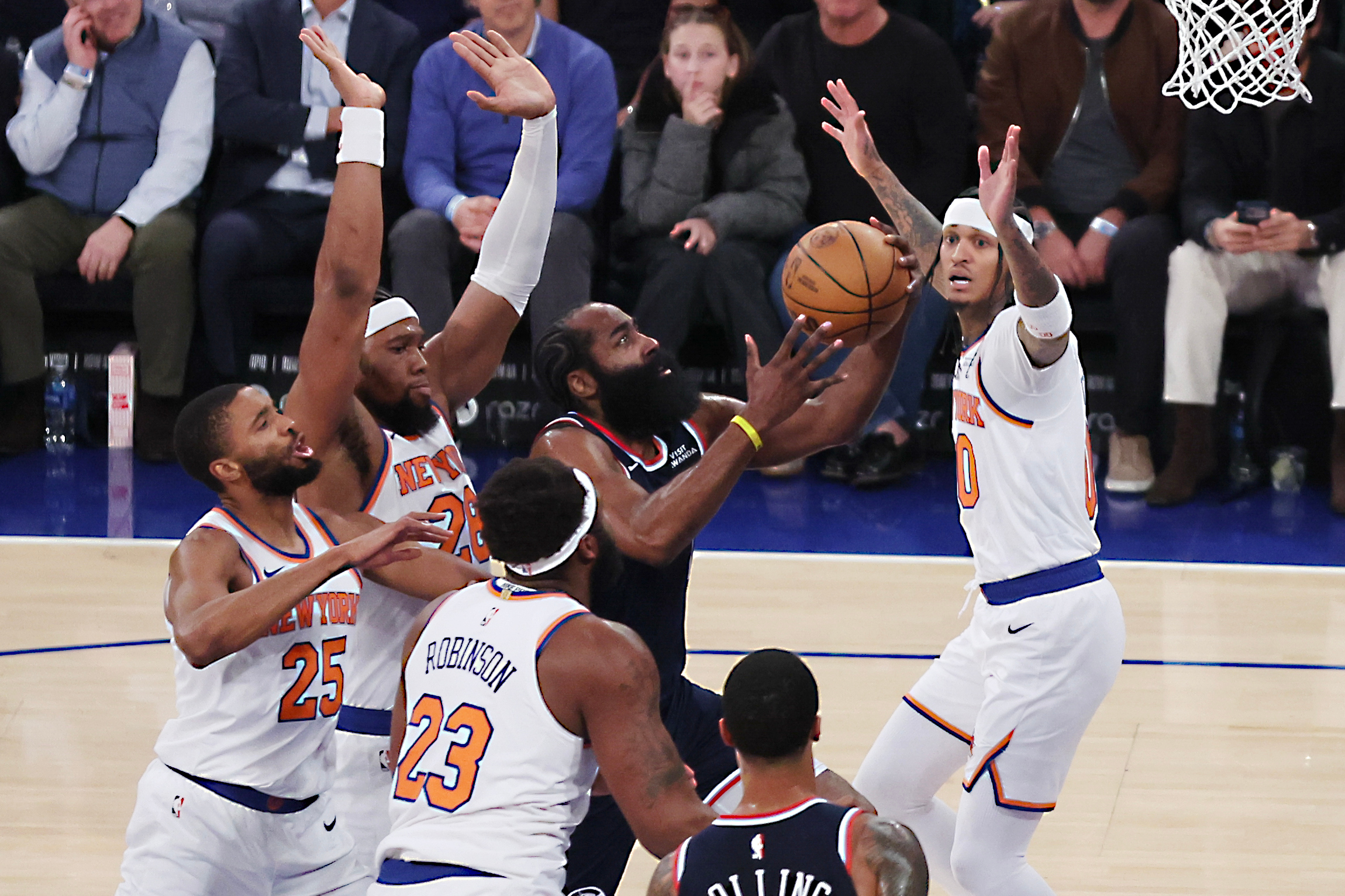 Clippers guard James Harden, center, drives to the basket surrounded...