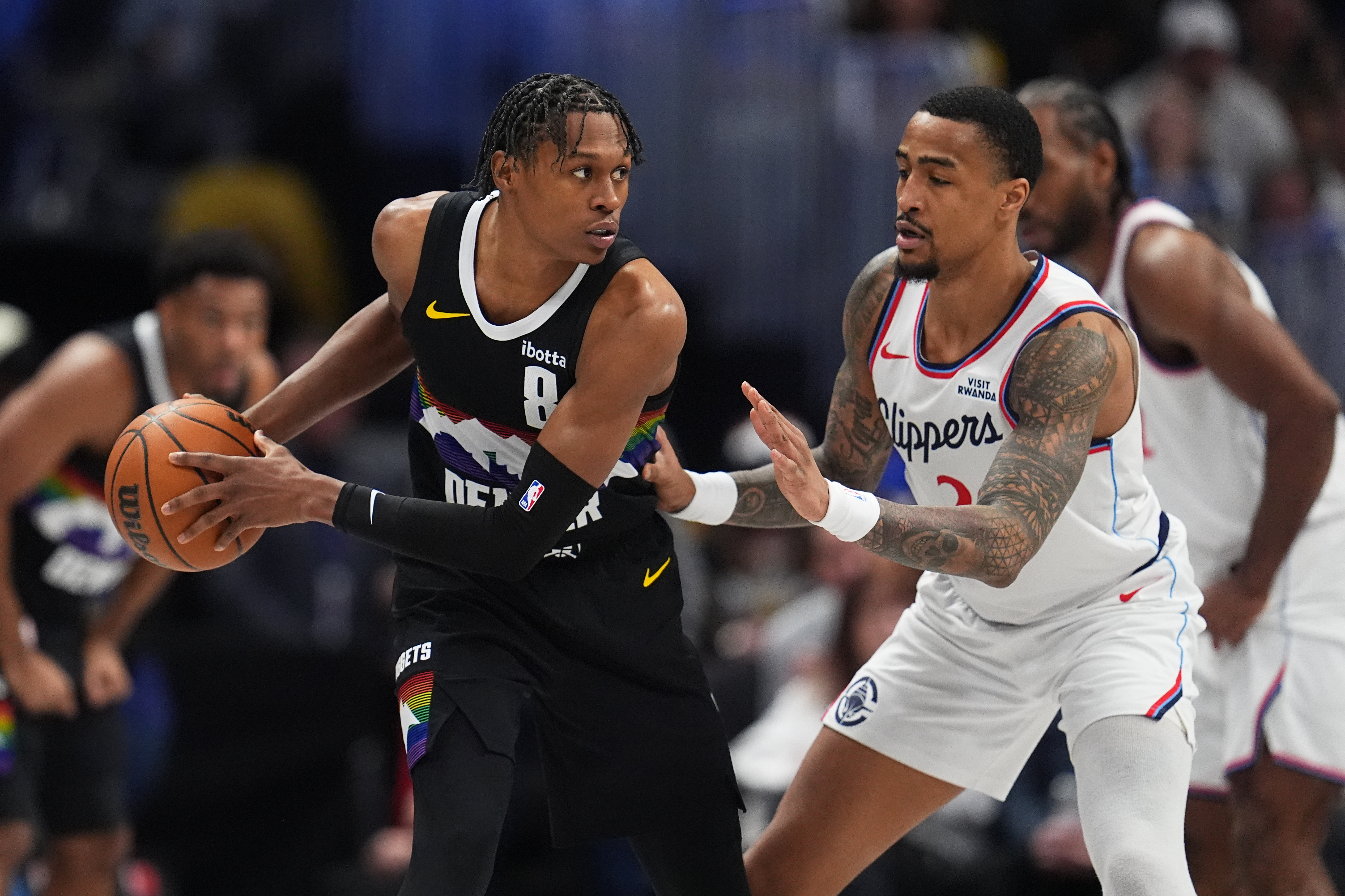 Denver Nuggets guard Peyton Watson, left, looks to pass the...