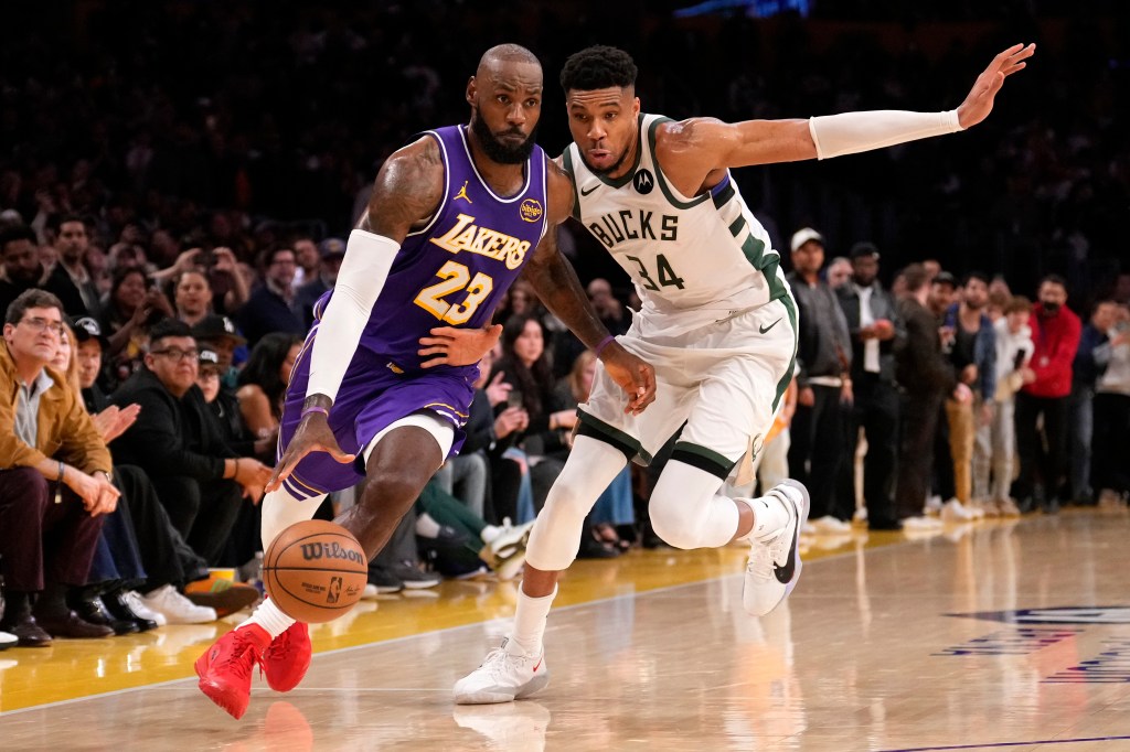 LeBron James of the Lakers dribbling past Giannis Antetokounmpo of the Bucks during a basketball game.