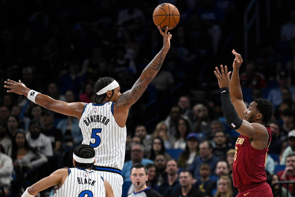 Orlando Magic forward Paolo Banchero (5) blocks a shot by Cleveland Cavaliers guard Donovan Mitchell, right, during the first half of an NBA basketball game, Saturday, Jan. 24, 2026, in Orlando, Fla. (AP Photo/Phelan M. Ebenhack)