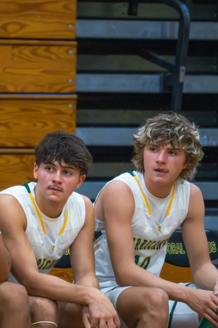 a group of young men sitting on top of a basketball court