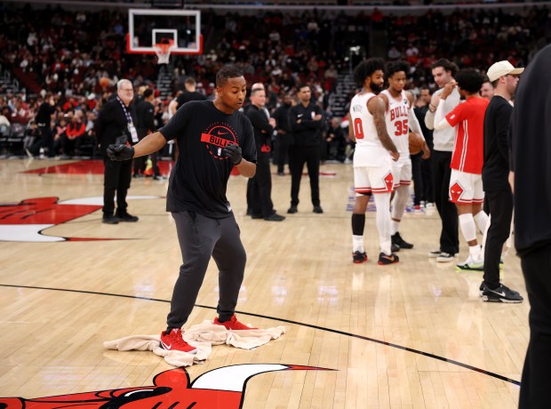 Chicago Bulls guard Coby White and forward/guard Isaac Okoro stand on the floor as a United Center worker uses a towel to dry the floor due to condensation before a scheduled start between the Bulls and the Miami Heat on Jan. 8, 2026. (Chris Sweda/Chicago Tribune)