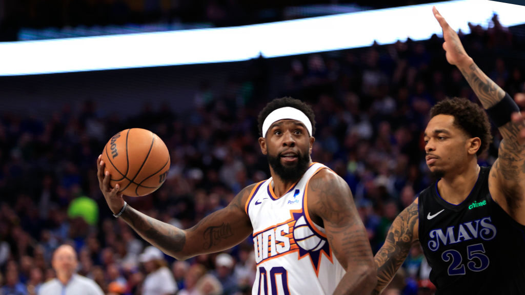 Royce O'Neale #00 of the Phoenix Suns drives inside for a shot against P.J. Washington #25 of the D...