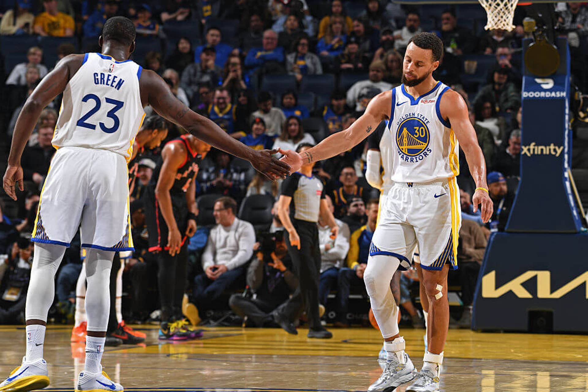 Draymond Green, left, and Steph Curry, right, high-five on the court during the Warriors' game against the Raptors.