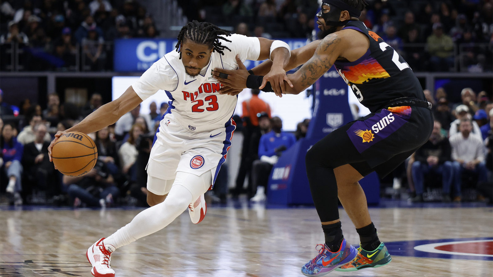 Detroit Pistons guard Jaden Ivey (23) dribbles defended by Phoenix Suns guard Jordan Goodwin (23) in the second half at Little Caesars Arena.