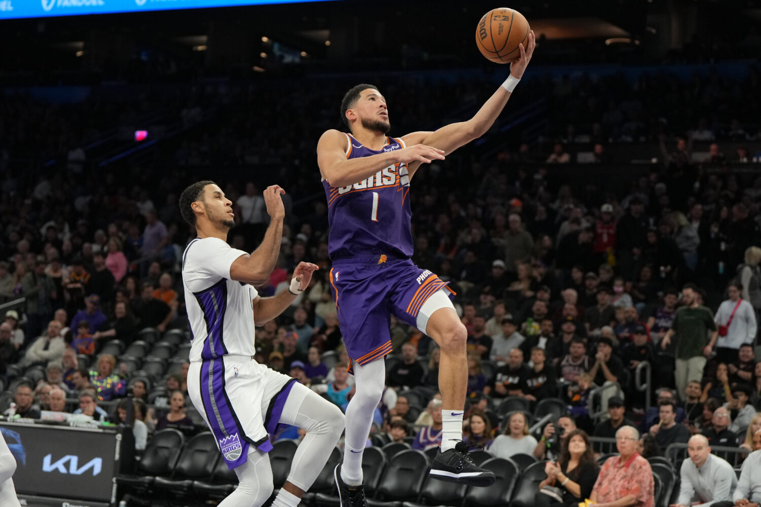 Phoenix Suns guard Devin Booker (1) drives past Sacramento Kings forward Keegan Murray, left, durin...