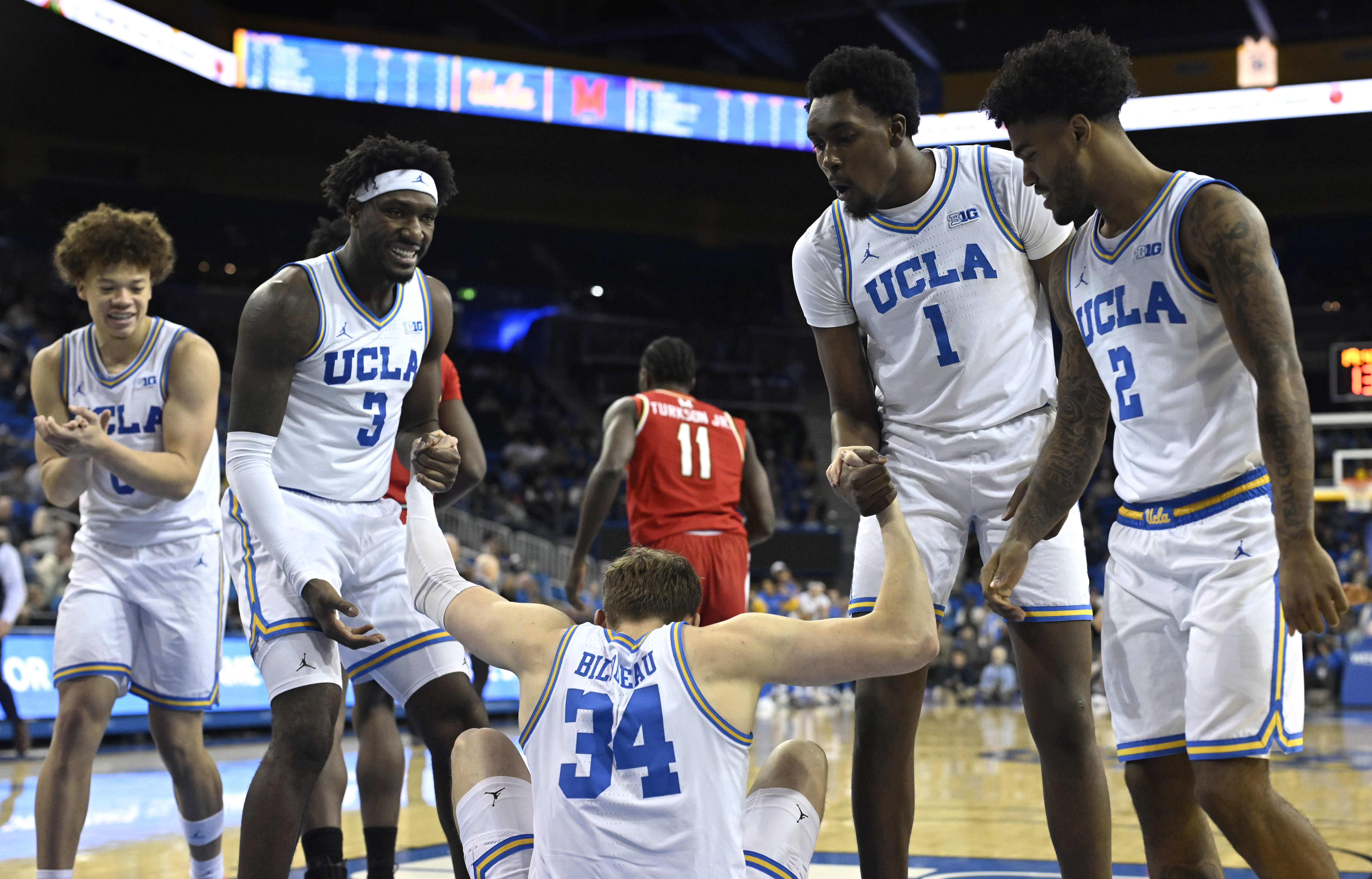Forward Tyler Bilodeau #34 of the UCLA Bruins is helped...