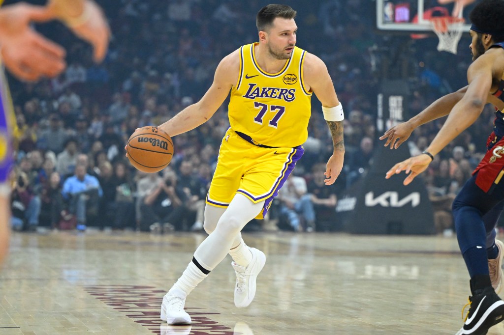 A Los Angeles Lakers player in a yellow jersey with number 77 dribbles a basketball on court.