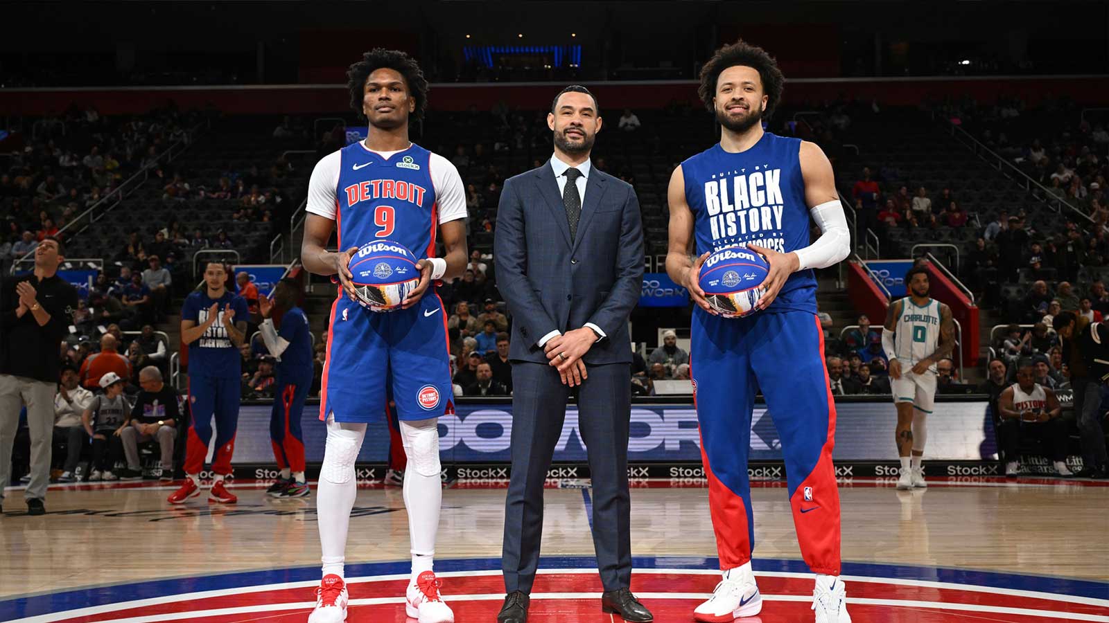 Detroit Pistons forward Ausar Thompson (9) and Detroit Pistons guard Cade Cunningham (2) stand at center court with Detroit Pistons President of Basketball Operations Trajan Langdon to be recognized for being named to the NBA All-Star Team before their game against the Charlotte Hornets at Little Caesars Arena.