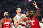 Portland Trail Blazers forward Deni Avdija, center, drives to the basket between Houston Rockets center Clint Capela, right, and guard Josh Okogie during the first half of an NBA basketball game in Portland, Ore., Wednesday, Jan. 7, 2026.