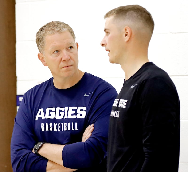 Utah State head coach Jerrod Calhoun, left, chats with former Aggie star and NBA player Sam Merrill before the start of USU’s early-morning practice Tuesday at the Wayne Estes Center in Logan.