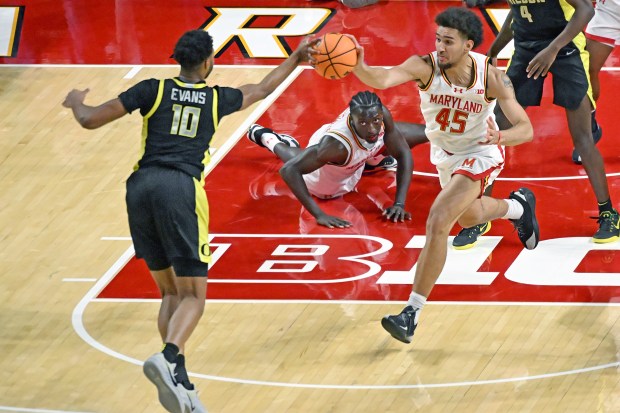 Oregon's Kwame Evans Jr. and Maryland's Collin Metcalf both get a hand on a loose ball as George Turkson, Jr. watches in the first half of a mens basketball game at the Xfinity Center. (Kim Hairston/staff)