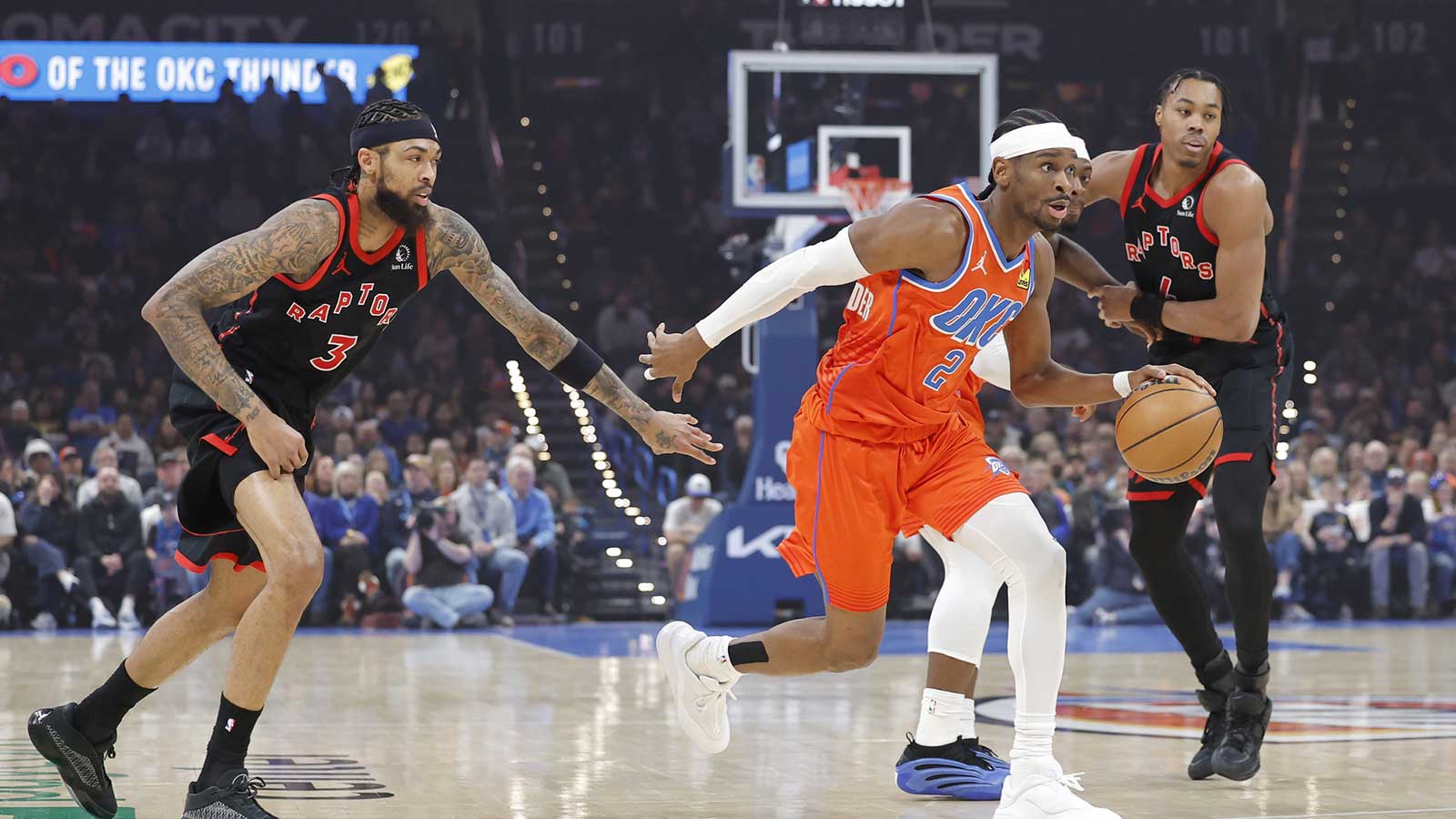 Thunder guard Shai Gilgeous-Alexander (2) drives between Toronto Raptors forward Brandon Ingram (3) and Toronto Raptors guard Scottie Barnes (4) during the first quarter at Paycom Center