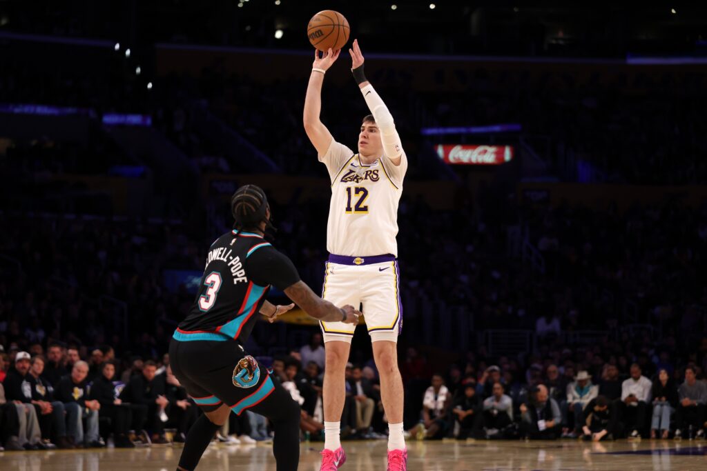 Jan 4, 2026; Los Angeles, California, USA; Los Angeles Lakers forward Jake Laravia (12) shoots the ball over Memphis Grizzlies guard Kentavious Caldwell-Pope (3) during the first half at Crypto.com Arena. Mandatory Credit: Kiyoshi Mio-Imagn Images
