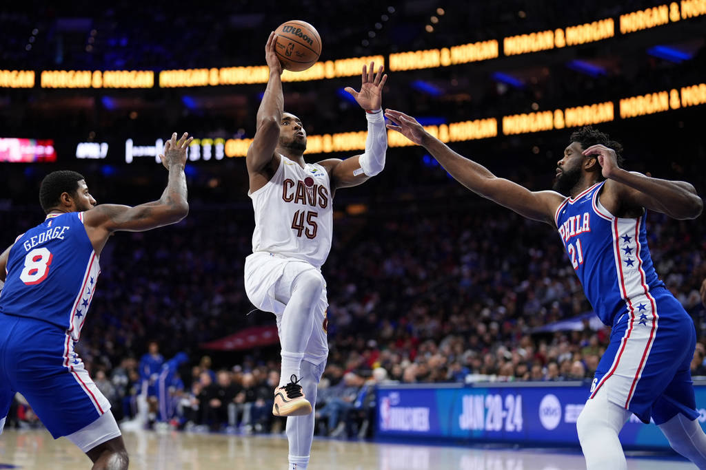Cleveland Cavaliers' Donovan Mitchell, center, goes up for a shot against Philadelphia 76ers' Joel Embiid, right, and Paul George during the second half of an NBA basketball game Wednesday, Jan. 14, 2026, in Philadelphia. 