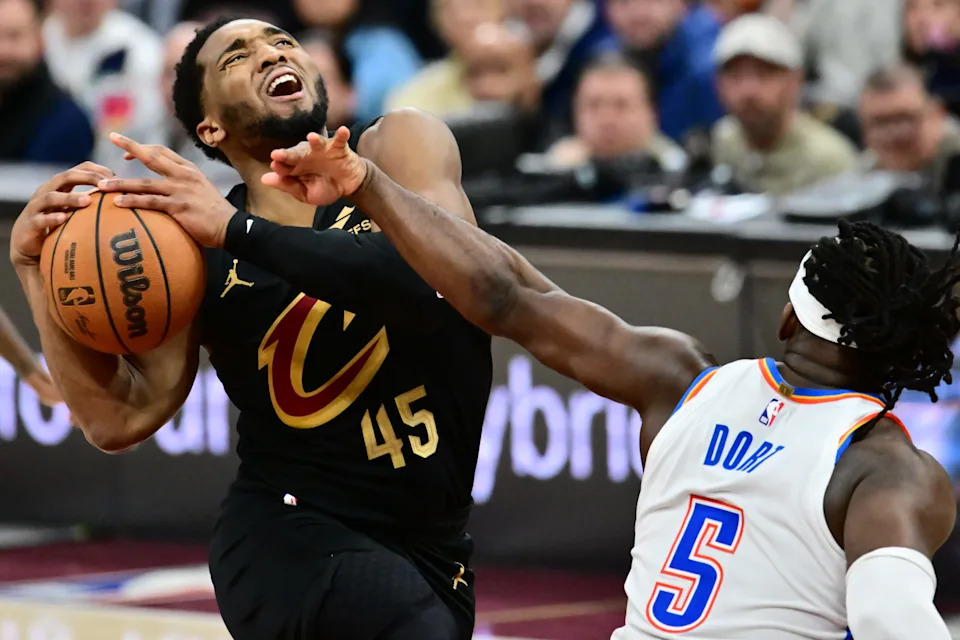 Jan 19, 2026; Cleveland, Ohio, USA; Cleveland Cavaliers guard Donovan Mitchell (45) drives to the basket against Oklahoma City Thunder guard Luguentz Dort (5) during the second half at Rocket Arena. Mandatory Credit: Ken Blaze-Imagn Images