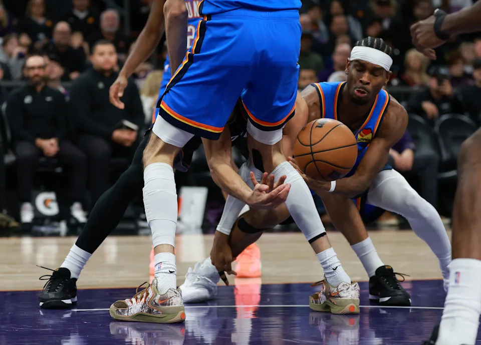 Jan 4, 2026; Phoenix, Arizona, USA; Phoenix Suns guard Devin Booker (1) passes the ball between the legs of Oklahoma City Thunder center Chet Holmgren (7) in the second half at Mortgage Matchup Center. Mandatory Credit: Mark J. Rebilas-Imagn Images