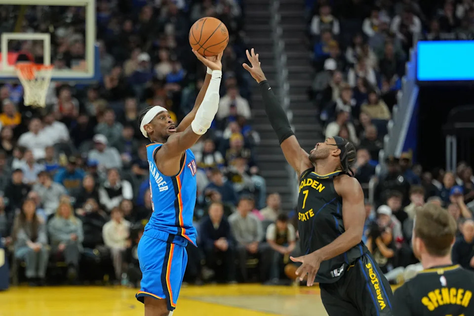 Jan 2, 2026; San Francisco, California, USA; Oklahoma City Thunder guard Shai Gilgeous-Alexander (left) shoots against Golden State Warriors guard Buddy Hield (7) during the fourth quarter at Chase Center. Mandatory Credit: Darren Yamashita-Imagn Images