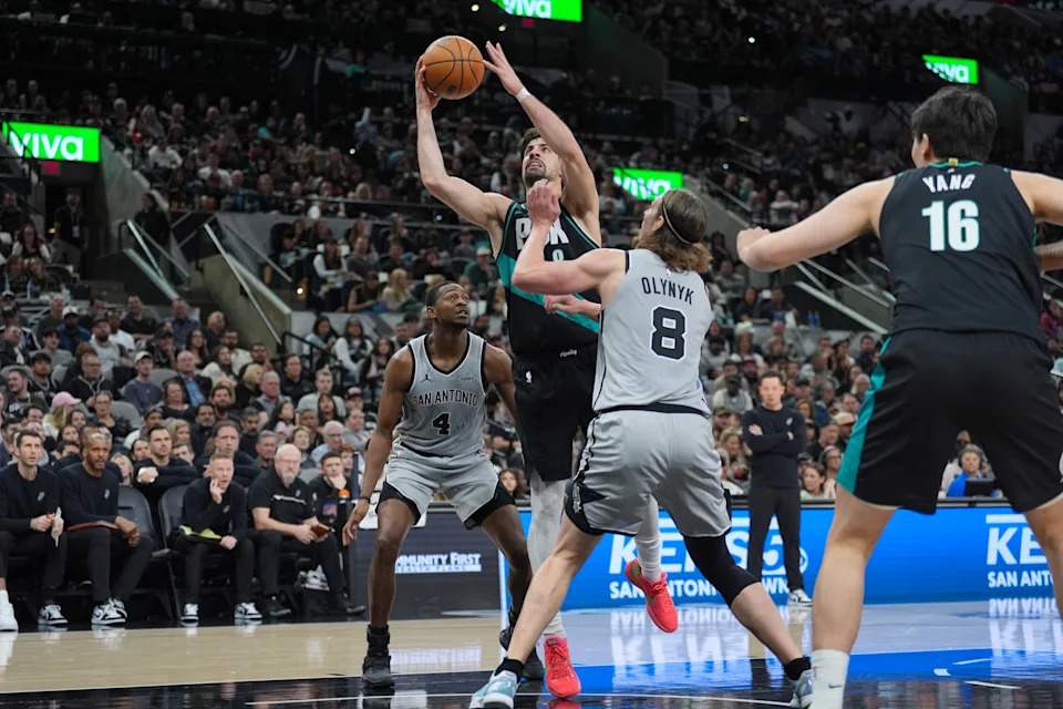 Jan 3, 2026; San Antonio, Texas, USA; Portland Trail Blazers forward Deni Avdija (8) shoots in between San Antonio Spurs guard De'aaron Fox (4) and forward/center Kelly Olynyk (8) in the second half at Frost Bank Center. Mandatory Credit: Daniel Dunn-Imagn Images