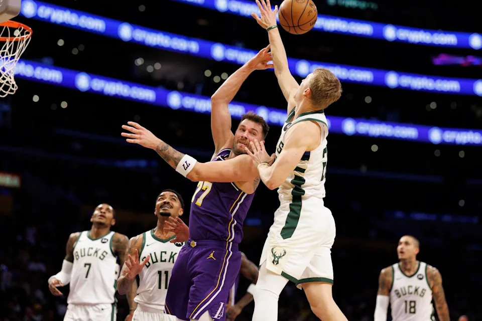 Lakers guard Luka Doncic, center, makes a backwards pass over Bucks guard AJ Green (20) during the first half Friday.