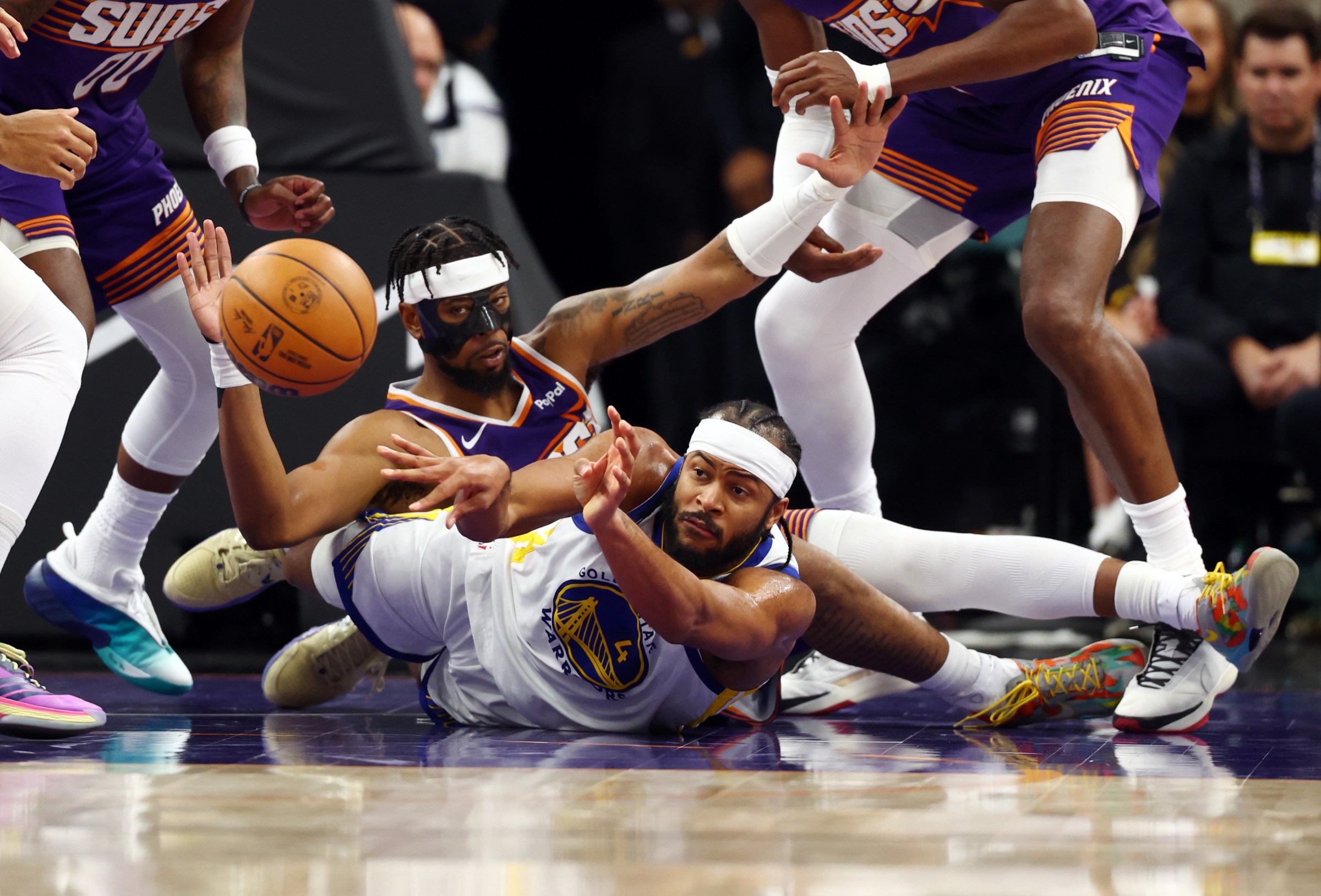 Dec 18, 2025; Phoenix, Arizona, USA; Golden State Warriors guard Moses Moody (4) battles for a loose ball against Phoenix Suns guard Jordan Goodwin (23) in the second half at Mortgage Matchup Center. Mandatory Credit: Mark J. Rebilas-Imagn Images