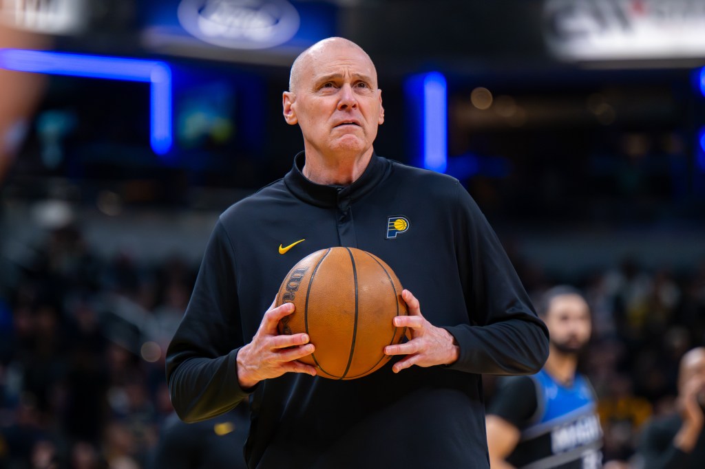 Indiana Pacers head coach Rick Carlisle looking toward the scoreboard while holding a basketball.