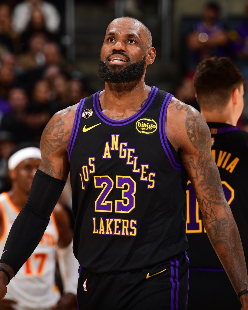 LeBron James in a black Los Angeles Lakers jersey with yellow and purple lettering looking up.