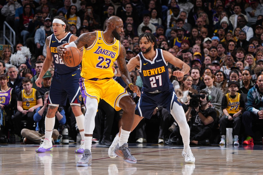 LeBron James of the Lakers dribbling the ball against two Denver Nuggets players during a game.