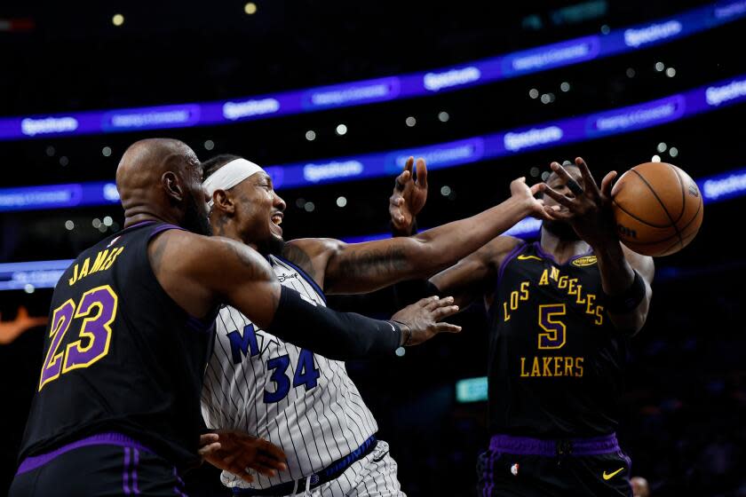 Orlando Magic center Wendell Carter Jr. (34) loses control of the ball while being guarded by Los Angeles Lakers forward LeBron James (23) and Los Angeles Lakers center Deandre Ayton (5) during the first half of an NBA basketball game Tuesday, Feb. 24, 2026, in Los Angeles. (AP Photo/Caroline Brehman)
