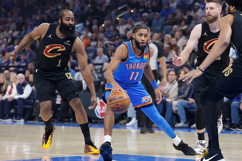 Feb 22, 2026; Oklahoma City, Oklahoma, USA; Oklahoma City Thunder guard Isaiah Joe (11) drives between Cleveland Cavaliers guard James Harden (1) and Cleveland Cavaliers forward Dean Wade (32) during the first half at Paycom Center. Mandatory Credit: Alonzo Adams-Imagn Images