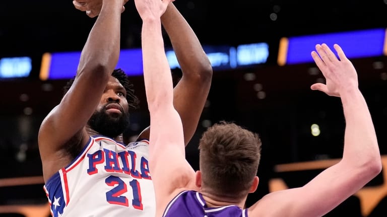 Philadelphia 76ers center Joel Embiid, left, shoots as Los Angeles...