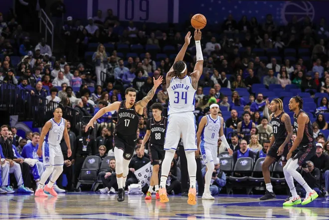 Feb 5, 2026; Orlando, Florida, USA; Orlando Magic center Wendell Carter Jr. (34) shoots a three point basket in front of Brooklyn Nets forward Michael Porter Jr. (17) during the first quarter at Kia Center.