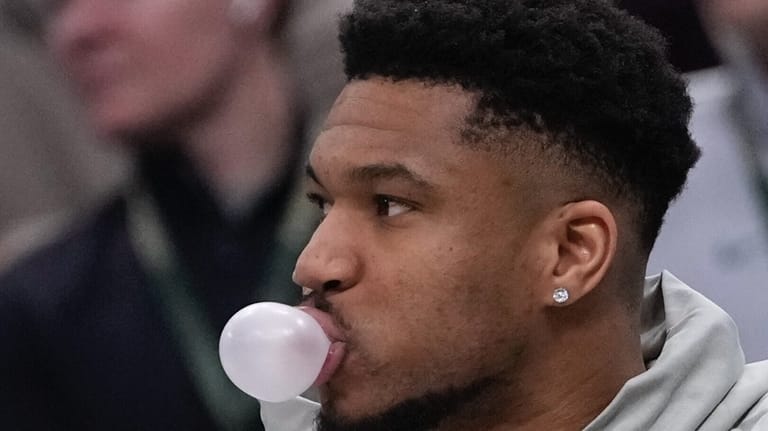 Milwaukee Bucks' Giannis Antetokounmpo blows a bubble on the bench...