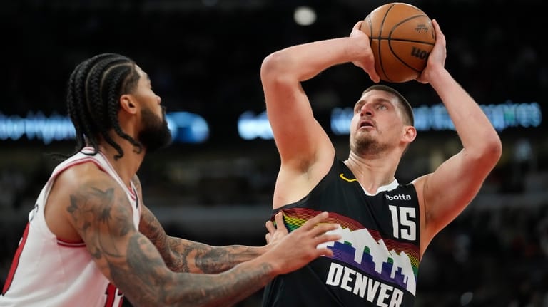 Denver Nuggets center Nikola Jokic (15), right, handles the ball...