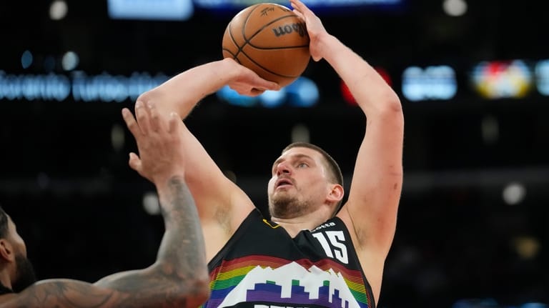 Denver Nuggets center Nikola Jokic (15), right, handles the ball...