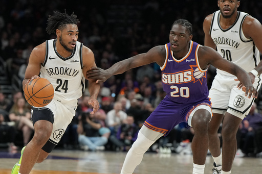 Brooklyn Nets guard Cam Thomas (24) drives on Phoenix Suns forward Rasheer Fleming (20) during the first half of an NBA basketball game, Tuesday, Jan. 27, 2026, in Phoenix. (AP Photo/Rick Scuteri)