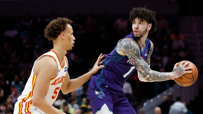 Charlotte Hornets guard LaMelo Ball, right, looks to pass the...