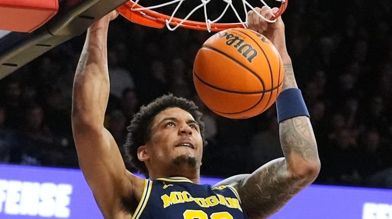 Michigan forward Yaxel Lendeborg hangs from the rim after dunking...