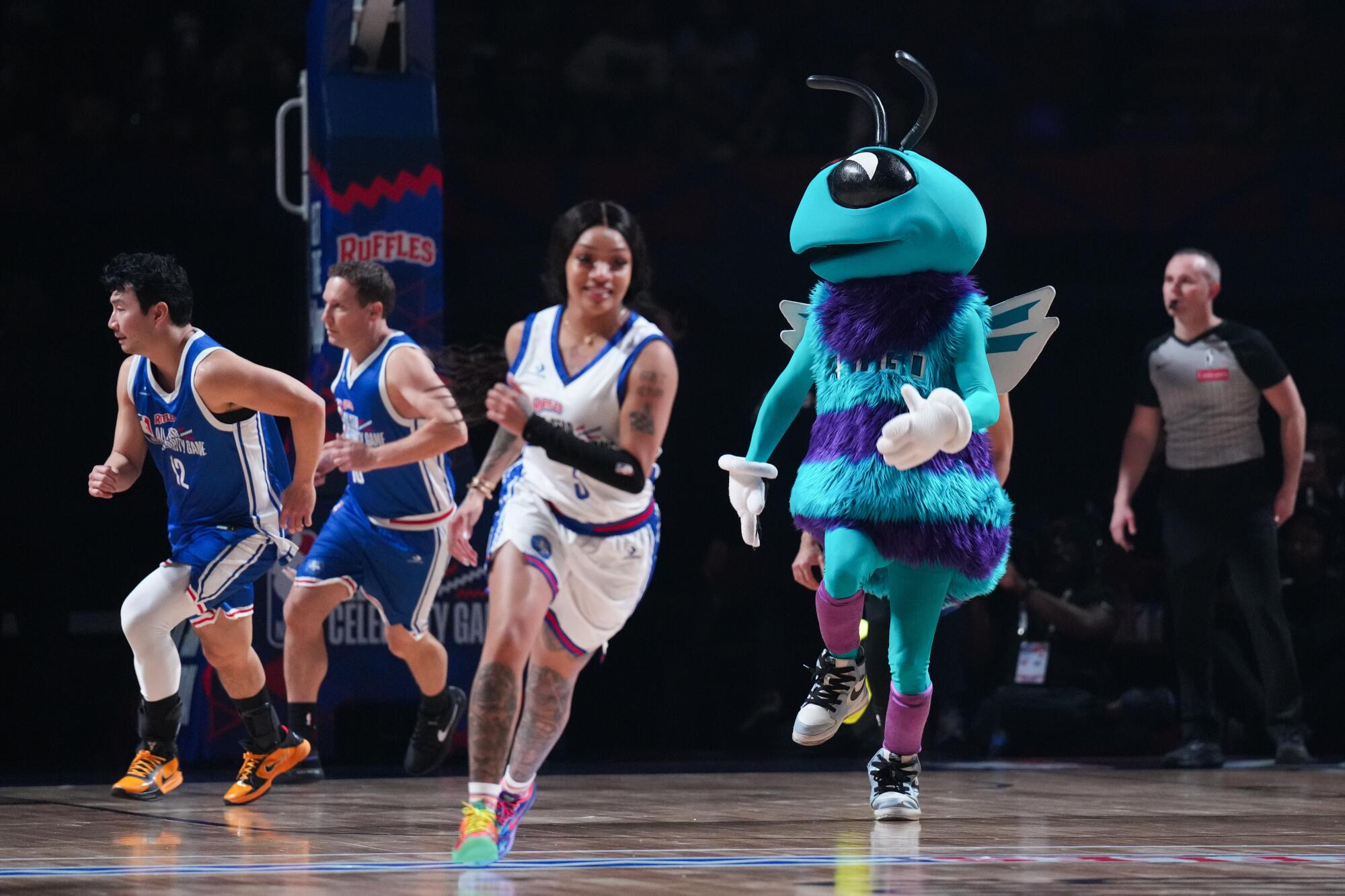 Hornets mascot Hugo jogs up the court next to Sparks player Rickea Jackson during the NBA All-Star Celebrity Game.