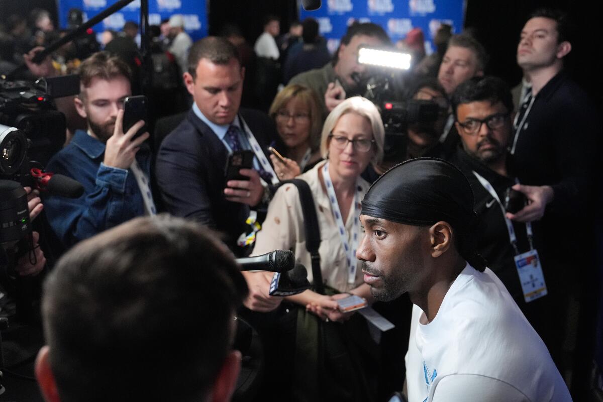 Clippers star Kawhi Leonard, right, is surrounded by reporters as he answers questions during All-Star Game media day.