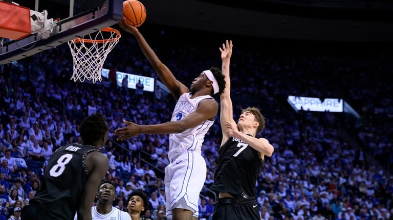 BYU forward AJ Dybantsa, center, goes to the basket as...