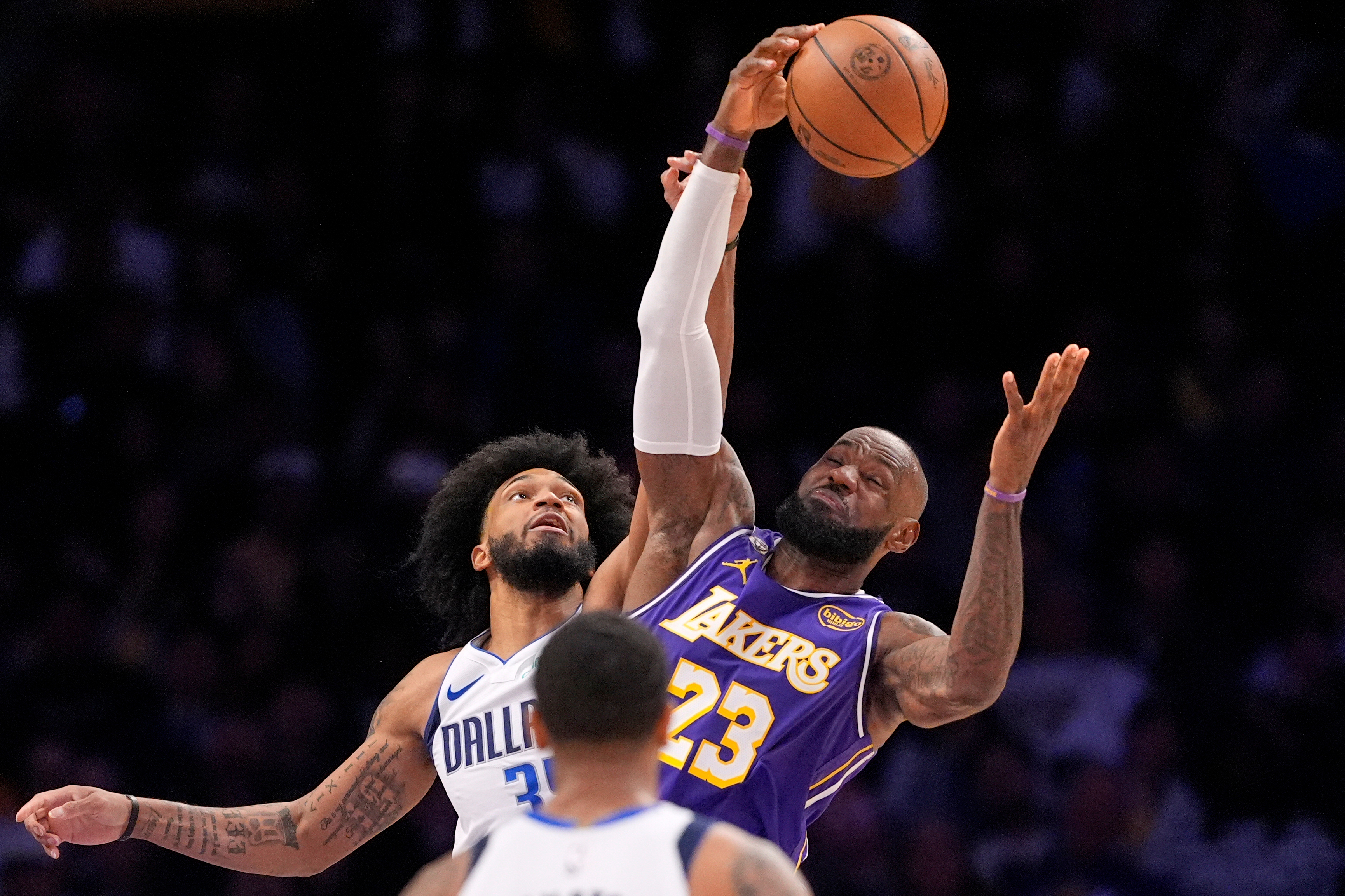 Lakers forward LeBron James, right, grabs a rebound away from...