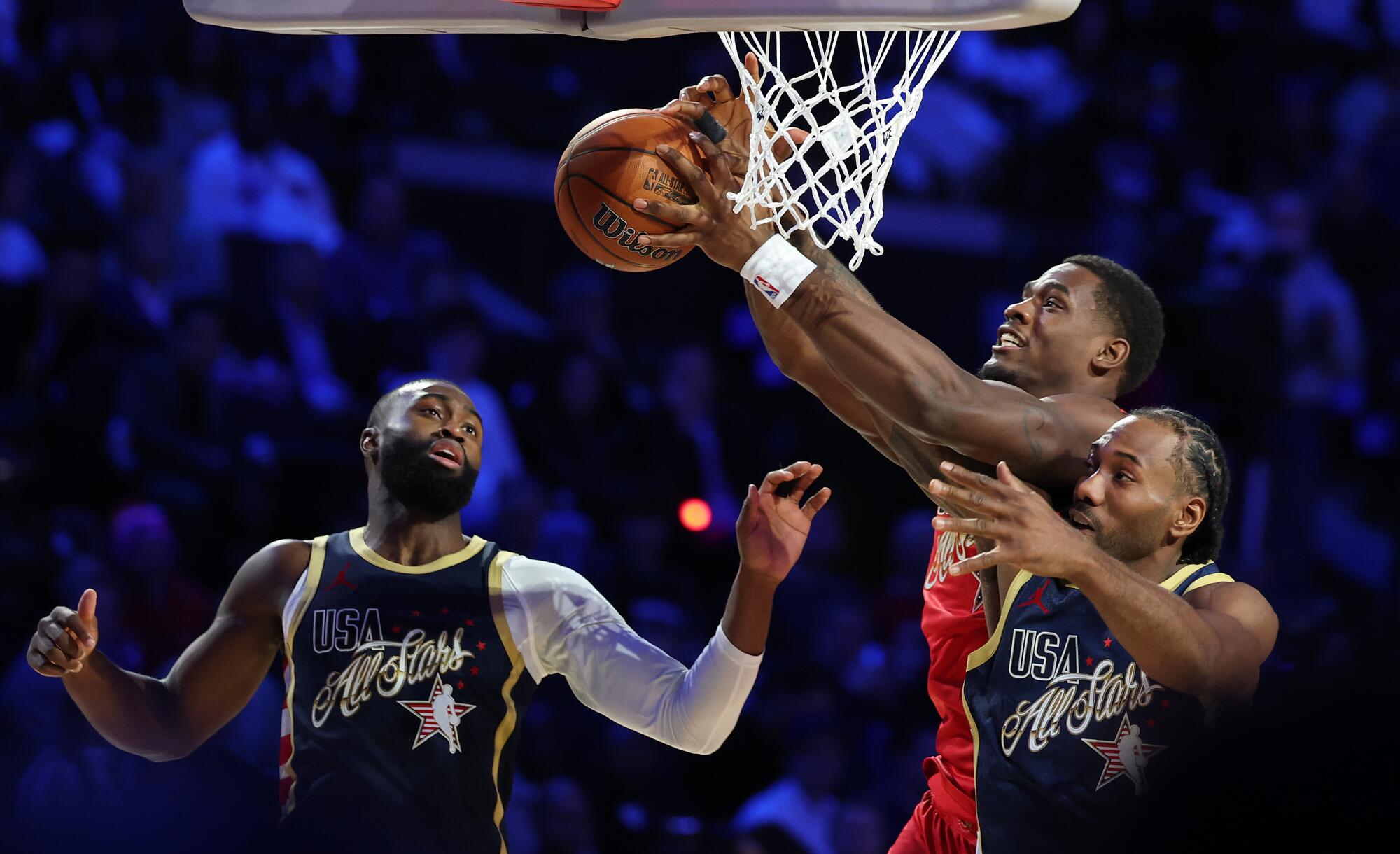 Team Stars' Jalen Duren, center, drives to the hoop as Team Stripes' Kawhi Leonard, right, and Jaylen Brown, left, defend.
