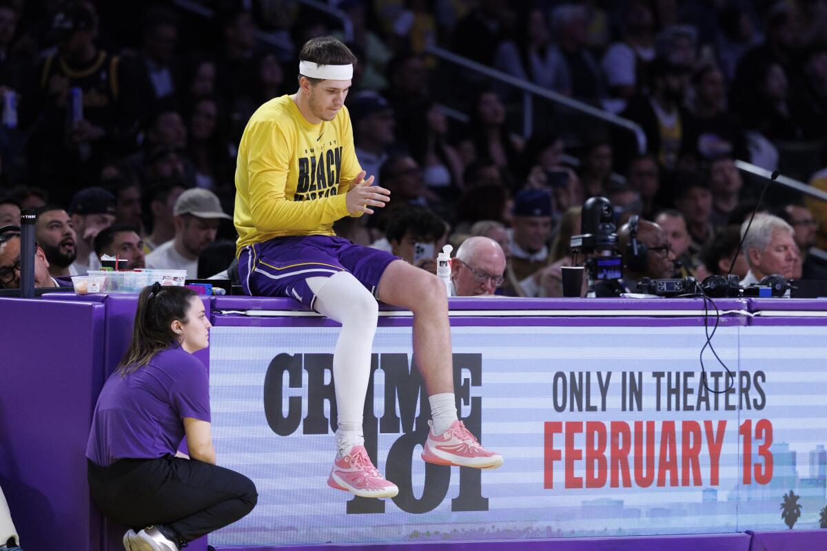 Lakers guard Austin Reaves sits on the scorer's table before entering a game against the Mavericks earlier this month.
