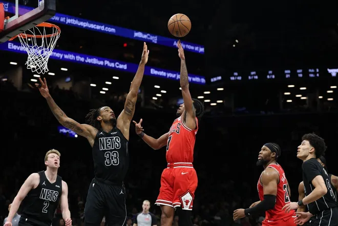 Feb 9, 2026; Brooklyn, New York, USA; Chicago Bulls guard Rob Dillingham (7) shoots the ball against Brooklyn Nets center Nic Claxton (33) during the first half at Barclays Center.